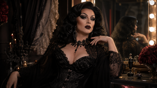 Drag Queen im Dark-Glam-Look mit dramatischem Make-up, voluminöser Perücke, schwarzem glitzerndem Outfit und auffälligem Schmuck im Backstage-Licht.